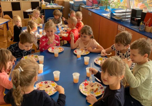 6 urodziny Zosi. Dzieci siedzą przy dwóch stołach i jedzą widelczykami tort. Obok tależyków stoją kubeczki z sokiem.